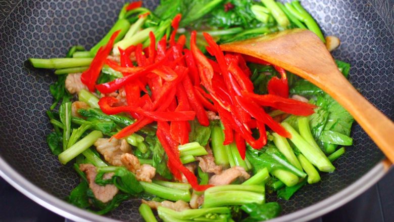 菜心红椒炒肉片,看见菜心断生变软的时候，加入红椒丝。