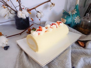 不易开裂的轻盈蛋糕卷,蛋糕卷顶端，用裱花嘴挤奶油花和草莓粒装饰。