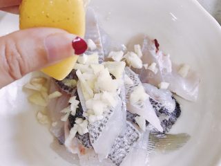 柠檬鱼,鱼肉用姜丝、蒜末、油、生粉、盐和柠檬汁腌