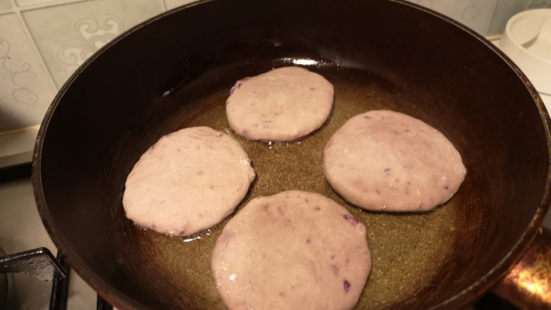 奶香拉丝紫薯饼,锅内放少许油，放入饼煎至金黄。