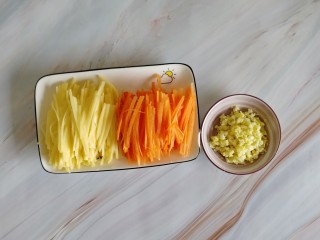 胡萝卜浓汤意面,把切好的胡萝卜丝、土豆丝、生姜大蒜末装盘，备用