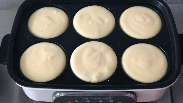 日式舒芙蕾松饼,多功能锅用六圆盘预热后，刷一层油，往圆盘里舀入一大勺面糊。用不粘平底锅也可以，面糊会自然形成圆形。