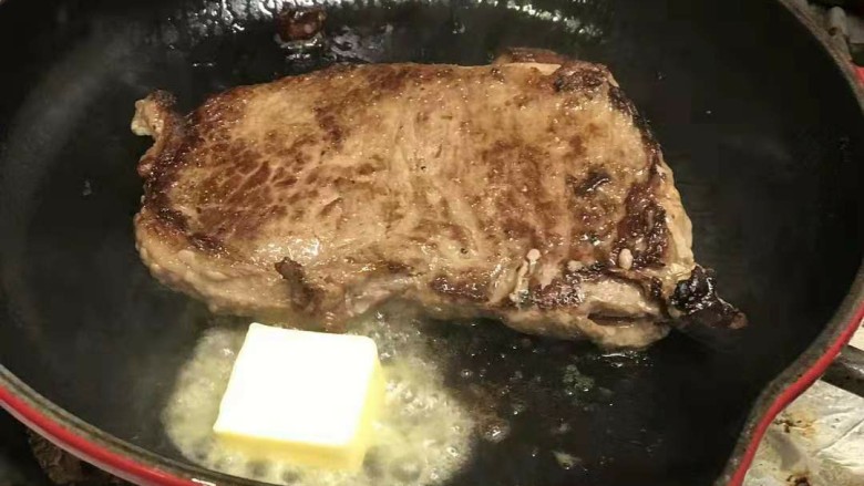 迷迭香黑胡椒牛排,等牛排表面有一点点焦的时候放入黄油，待黄油融化，将牛排二面都沾上黄油