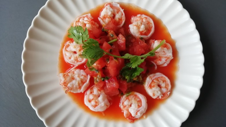 西红柿百香果凉拌虾,将搅拌均匀的汁淋在摆好盘的虾仁上，放香菜点缀一下。