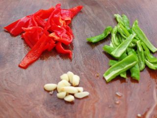 双椒肉片炒花菜,把青椒和红椒切成丝，大蒜去皮后切片。