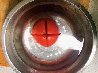番茄丝瓜补钙粥,番茄清洗干净，在背部划十字刀。放在碗中用开水浸泡一分钟，去掉番茄皮。 再换成凉水降温去皮。