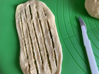 椰蓉面包卷,擀成长舌状，用面包刀切几刀，注意两头不要切断。