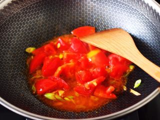 自制丸子一锅炖,锅烧热后倒入花生油烧热，爆香葱姜丝，加入番茄块大火翻炒至变软。