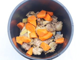 山药香菇玉米土鸡汤,鸡肉连同姜片一起放入锅中，加上胡萝卜。