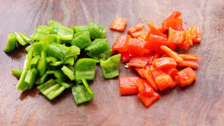 茄丁双椒炒肉丁,把青红椒洗净后去籽，用刀切成小块。