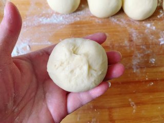 发面豆沙油酥饼,取一个小面团，用手压成中间厚四边薄的圆饼状，包入适量的油酥，像包包子的手法一样捏紧收口。