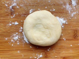 发面豆沙油酥饼,再用手压扁，用擀面棍擀成长条形，将长条形面团竖起来，用手压扁，擀开擀大。