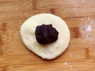 发面豆沙油酥饼,包入适量的豆沙馅，也是跟裹油酥的方法一样整成圆形，用手按扁成圆饼状。
