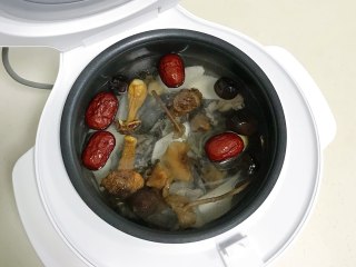 菌菇山药乌鸡汤,加入姜片、香菇、松茸、茶树菇、红枣和山药，倒入适量的清水，建议不要超过最高水位线。