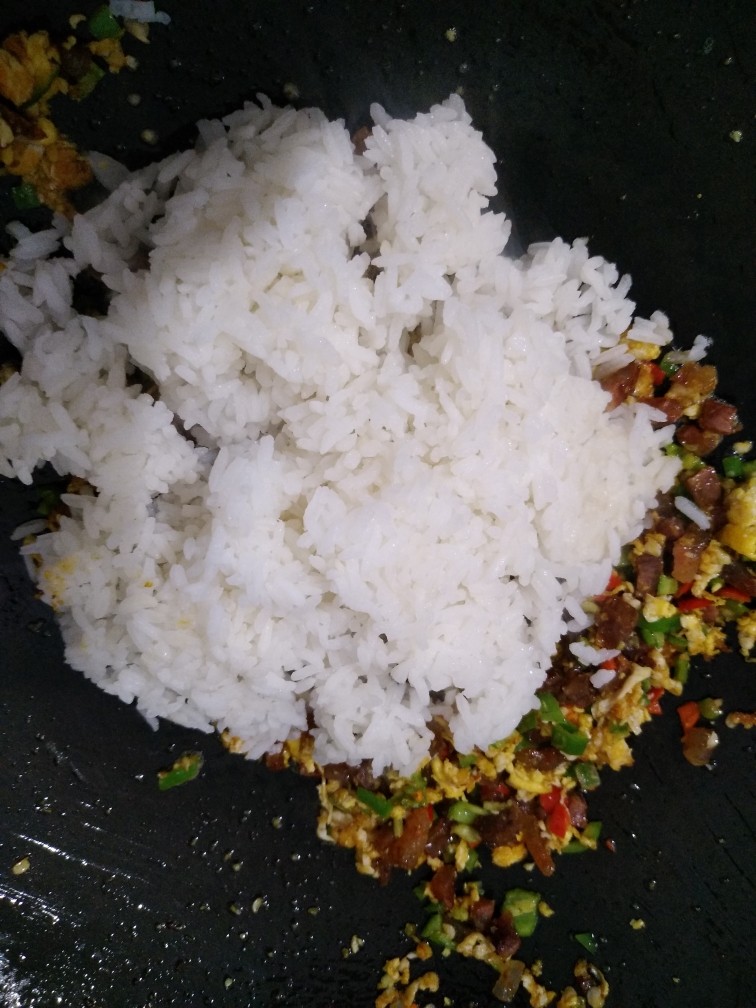 香肠鸡蛋炒饭,倒入米饭一起翻炒，把米饭炒散，看到米饭在锅里跳动
