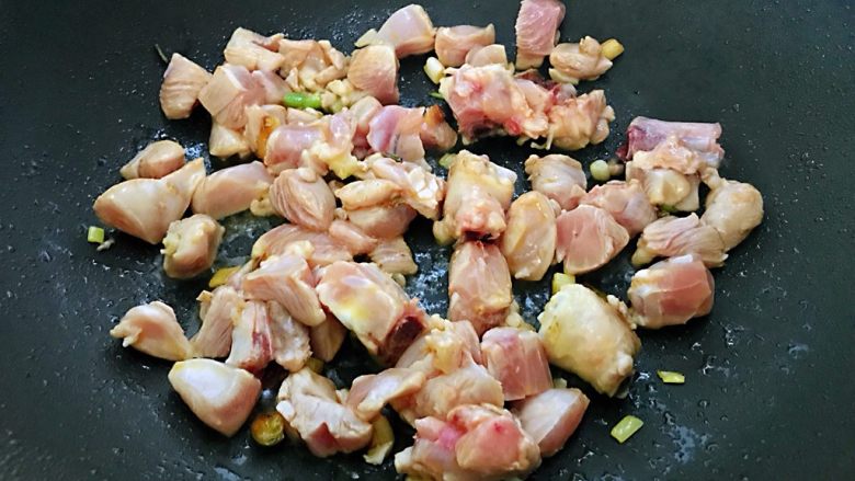 鸡腿焖米饭,锅烧热，加入少量油，放入葱爆炒出香味，加入腌制好的鸡腿炒至肉变色。