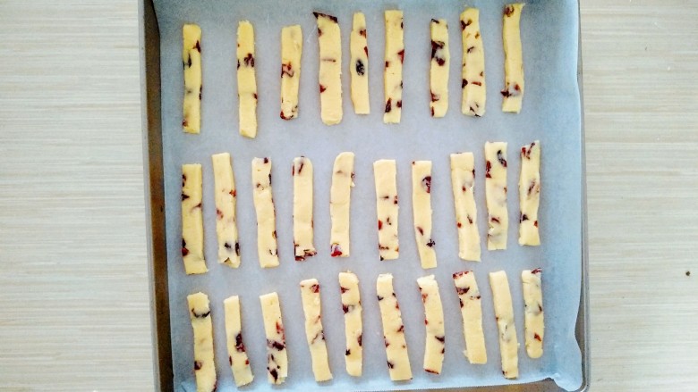 蔓越莓奶酥条,冷冻成型之后用刀切成小长条。均匀的摆放在烤盘里。