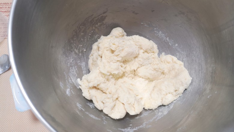 酸奶菠萝芝士土司,先开低档打面，大概两三分钟把原料搅拌均匀，如果面团如图状态，剩余牛奶就可以不加了，如果还略有一点干粉，或者手感不太软就要加入剩余牛奶。