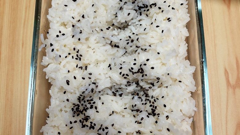 金枪鱼胚芽米寿司 | 便当,将米饭盛出来放入碗中，撒上一些黑芝麻。