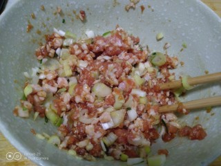 猪肉韭菜水煎包,猪肉馅中加入葱、姜碎，加入香油搅拌均匀。