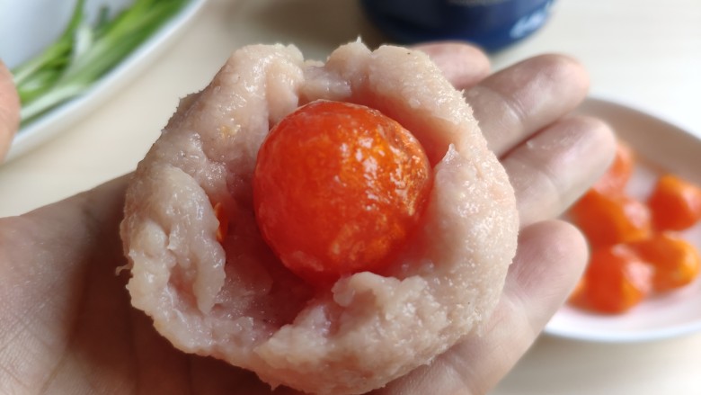 一颗有“内涵”的莲藕丸子,取适量肉馅中间按个坑，包上一颗鸭蛋黄，团成圆球状。