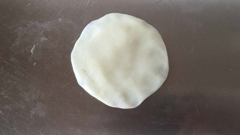 莲蓉蜜豆冰皮月饼,取一个冰皮将其压扁，边缘稍微薄一些。