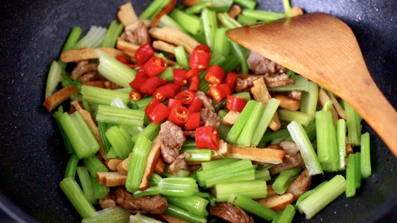 豆干肉片芹菜小炒,打开锅盖，加入焯过水的芹菜和小红尖椒丁。