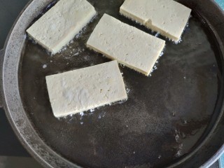 铁板豆腐,铁板或者平底锅烧热倒入油，将豆腐一块块摆入开始煎豆腐。