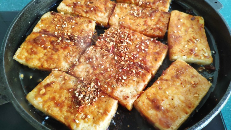 铁板豆腐,两面都刷上酱料后，撒上调好的芝麻辣椒粉。