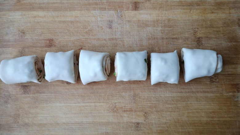 腐乳葱香饼,用刀把卷好的圆桶，切成大小均匀的段。