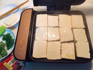 铁板豆腐,将豆腐从盐水里捞出，用厨房纸吸干水份。
油热之后把豆腐片一块块摆上去，
在豆腐表面继续刷一层油。