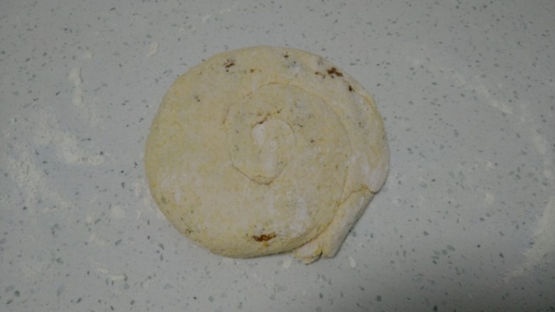 玉米面芝麻酱饼,从底部卷起，再从一端卷起，用手压扁。