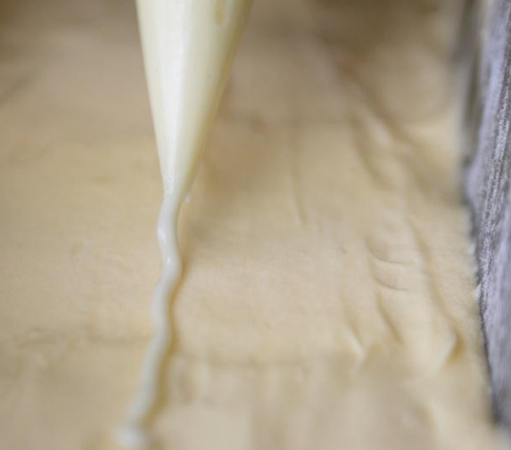 柠檬糖霜磅蛋糕,在麵糊表面的中间，挤一条、或切一条细长的奶油，可帮助烘烤时裂纹比较漂亮