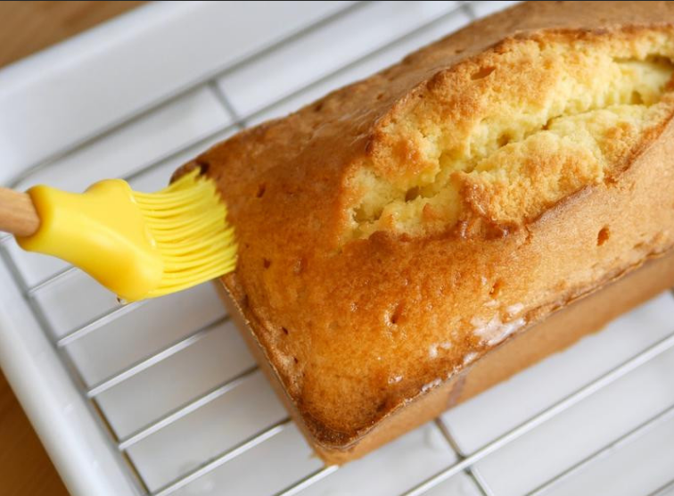 柠檬糖霜磅蛋糕,出炉后的磅蛋糕先放10-15分鐘，时间到脱模，用竹叉在上面戳几个洞，趁蛋糕还热涂上柠檬糖浆，放至完全凉透