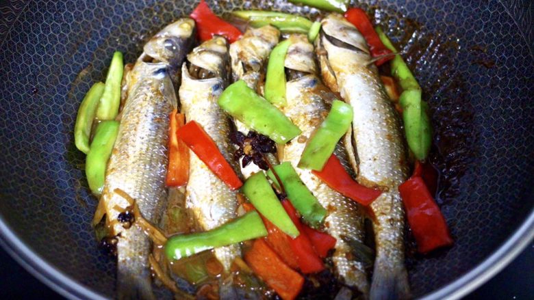 家常酱焖梭鱼,看见锅中汤汁收干，青红辣椒变色断生的时候，即可关火。