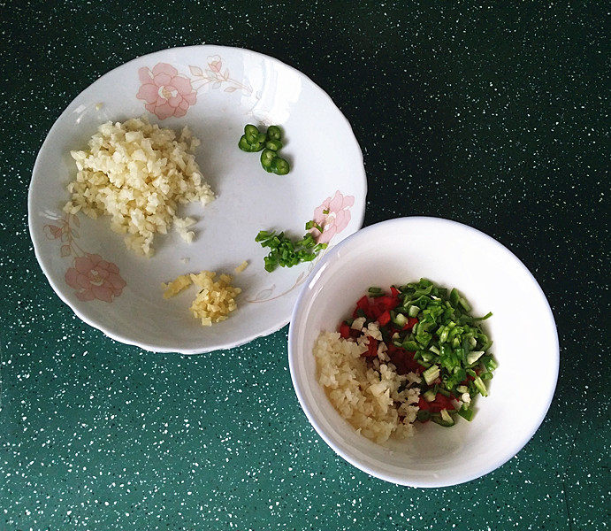 蒜香青口贝,将青红椒碎丁和部分蒜蓉等放入小碗中，余下蒜蓉放另一盘中，如图
