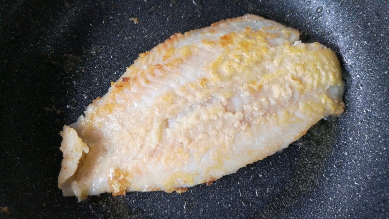 家庭版自制烤鱼,锅中适量油烧热，给腌制好的龙利鱼外面薄薄裹一层裹炸粉后入锅。中小火煎至两面金黄挺实后盛出备用。