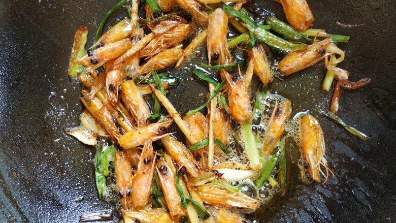 鲜美好吃的什锦鲜虾粥,起锅烧油，倒入虾头葱段姜丝煸炒出香味，如图即可，盛出撒椒盐做配菜。