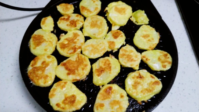 土豆、鸡蛋椒盐小饼,电饼铛均匀涂上食用油，放入土豆片，煎至一面金黄。