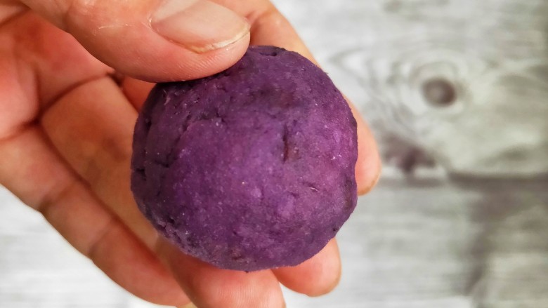 奶香紫薯糯米球,把紫薯糯米团分成小份，包上加入奶粉的紫薯馅，揉成团。