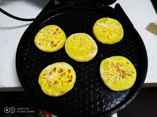 南瓜紫薯饼,涂上清水粘上芝麻，放入预热好的电饼铛中。