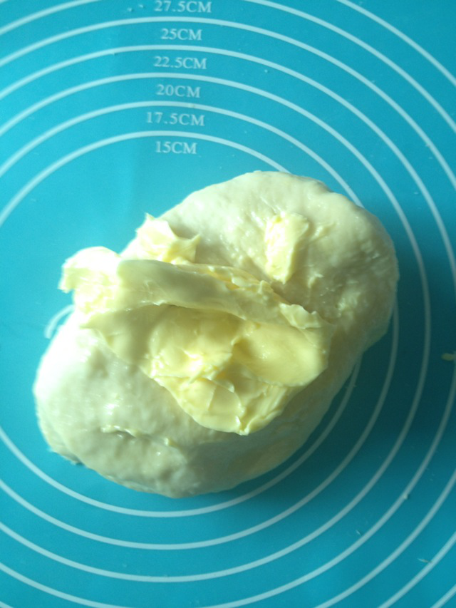 黄油牛角包,面团揉到可以扩展的阶段后，加入黄油，继续揉。