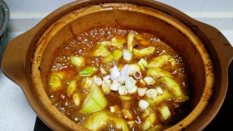 猪蹄汤炖丝瓜、扁豆,放入蒜片、葱碎 。