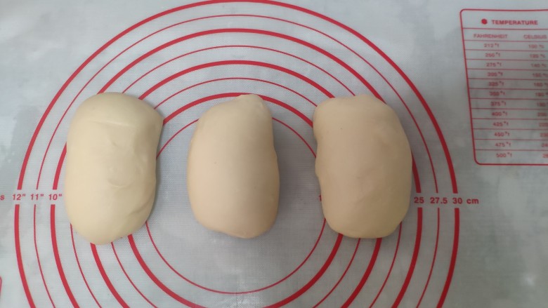 一次发酵手撕吐司面包,取出整理，等分为3份，分别滚圆后盖保鲜膜松弛约3分钟。
