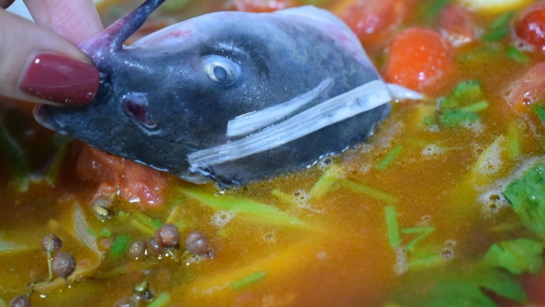 泰式风味口蘑钳鱼,【菜品制作7】放入鱼头，和锅内其他食材一起熬制泰式风味番茄柠檬生椒汤底儿