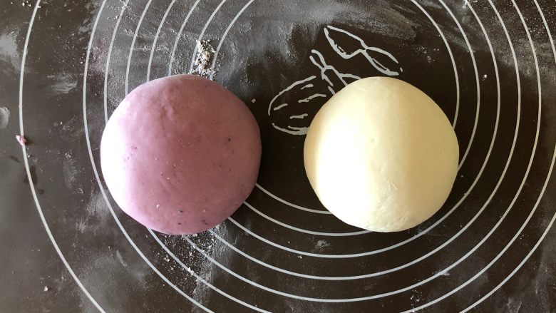 双色肠仔馒头卷,把揉好的面团平均分成两份，其中一份揉进紫薯粉，由于紫薯粉比较干，可以滴几滴清水再揉，揉至颜色均匀，然后两个面团分别揉圆。