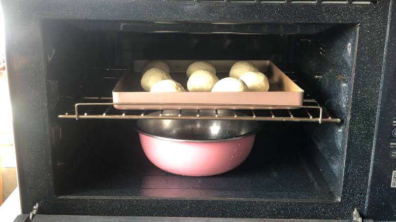 日式红豆包,把烤盘放到烤箱中，并放入一盆热水，进行二次发酵。
 