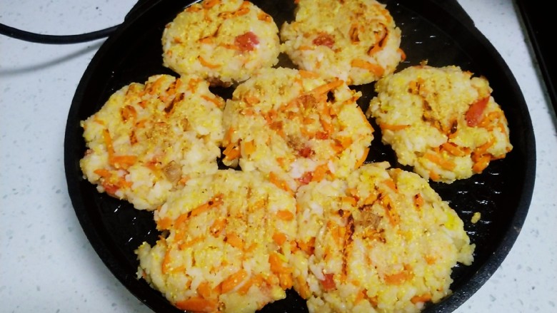 大米、胡萝卜、鸡蛋饼,电饼铛预热，用手将大米蔬菜团圆再压成小饼，放入电饼铛中 。