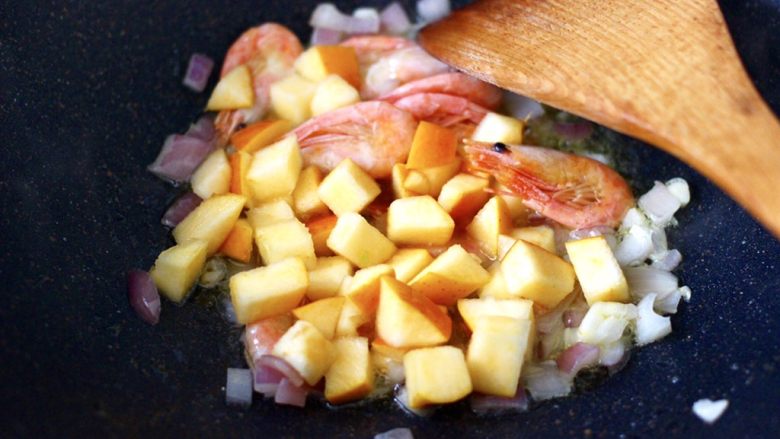 苹果北极虾时蔬炒饭,这个时候加入苹果丁，继续大火翻炒片刻。