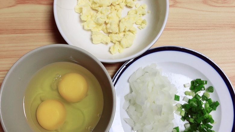 鸡蛋抱饺,煎饺子时，准备其他食材，将洋葱、小葱切碎备用。鸡蛋打入碗中。